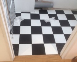An image of a bathroom which has been fitted with some new plumbing and a new tile patter vinyl floor